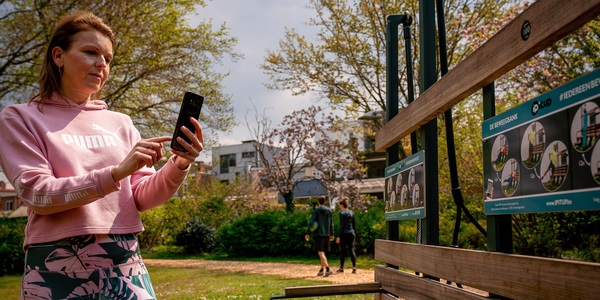 Vrouw kijkt op haar gsm aan de beweegbank